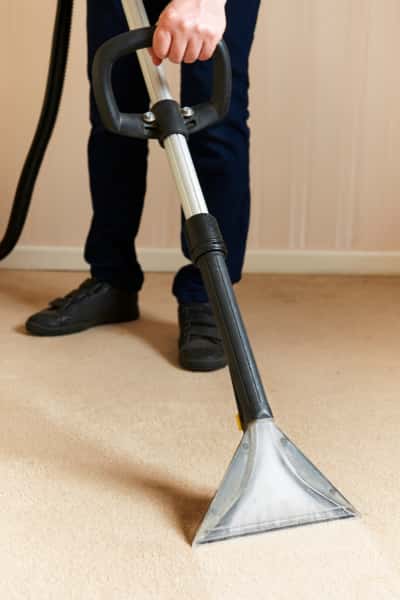 This is a photo of a man steam cleaning a cream carpet, using a professional steam cleaning machine carrying out by Blackheath Carpet Cleaning.